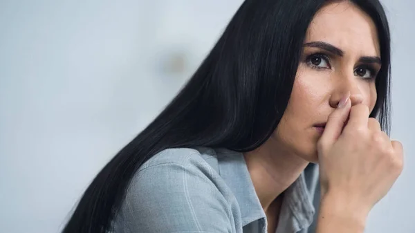 Worried woman biting nail and looking away at home — Stock Photo