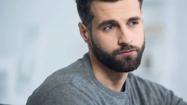 Sad and bearded man thinking while looking away at home — Stock Photo