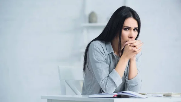 Verärgerte Frau mit geballten Händen sitzt neben Taschenrechner auf Schreibtisch — Stockfoto