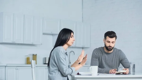 Mujer disgustado gesto cerca de hombre con calculadora - foto de stock