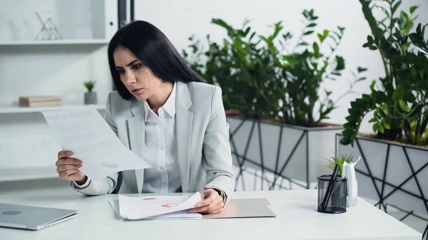 Mujer de negocios preocupada mirando los documentos en la oficina - foto de stock