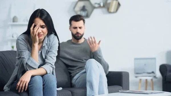 Bouleversé femme pleurer près flou et mécontent copain querelle à la maison — Photo de stock