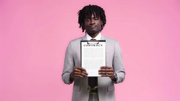 Afroamericano uomo d'affari mostrando contratto isolato su rosa — Foto stock