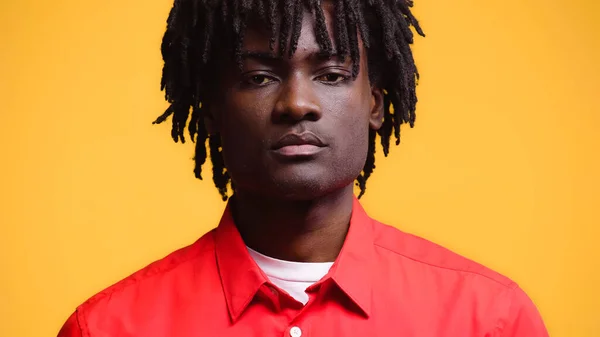 Portrait of african american man with dreadlocks in red shirt isolated on yellow — Stock Photo