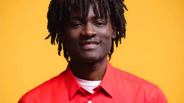 Homem americano africano feliz na camisa vermelha que sorri isolado no amarelo — Fotografia de Stock