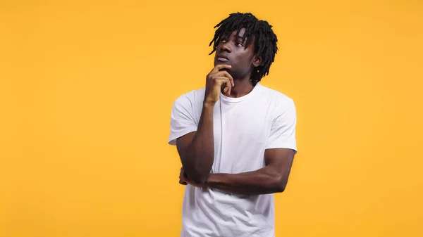 Pensive young african american man in white t-shirt looking away isolated on yellow — Stock Photo