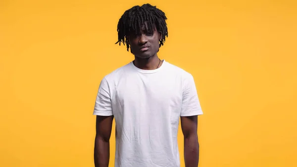 Dissatisfied young african american man in white t-shirt isolated on yellow — Stock Photo