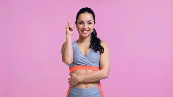 Fröhliche junge Frau in Sportkleidung, die mit dem Finger auf rosa zeigt — Stockfoto