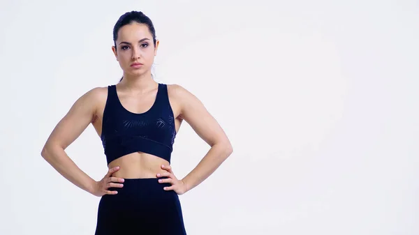 Mujer joven disgustado en ropa deportiva de pie con las manos en las caderas aisladas en blanco - foto de stock