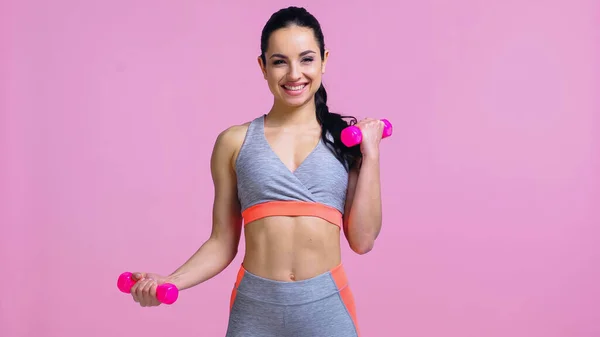 Desportista alegre trabalhando fora com halteres isolados em rosa — Fotografia de Stock