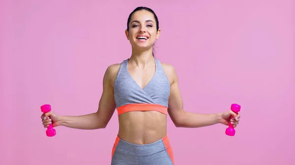 Positive Sportlerin trainiert mit Hanteln isoliert auf rosa — Stockfoto