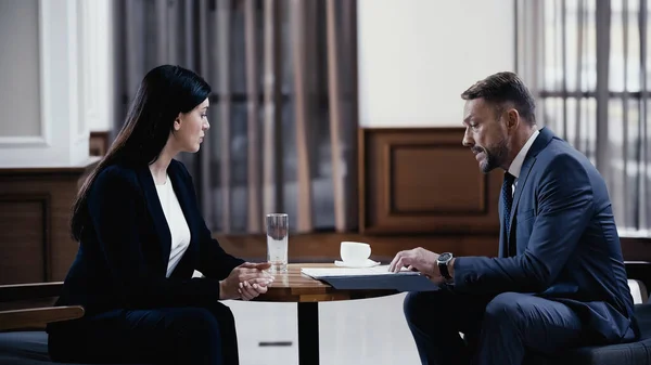 Man and woman in suits discussing work in lobby of restaurant during business meeting — Stock Photo