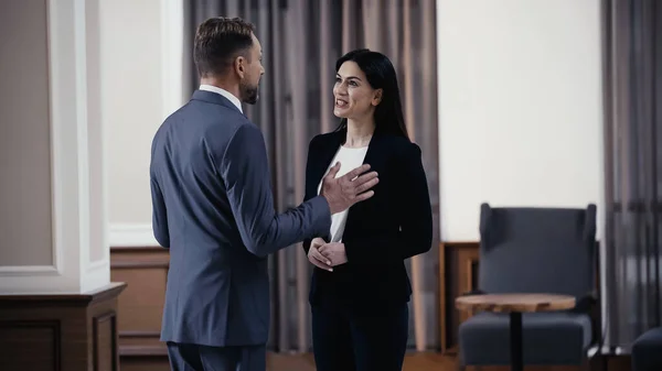 Joyful businesswoman talking with businessman in lobby of restaurant - foto de stock