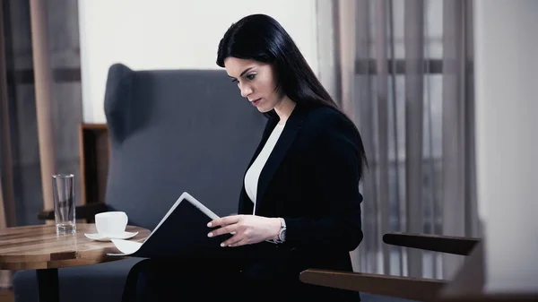 Brunette businesswoman looking at paper folder with documents in restaurant — Photo de stock