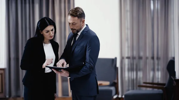 Business partners looking at documents in paper folder in lobby of restaurant - foto de stock