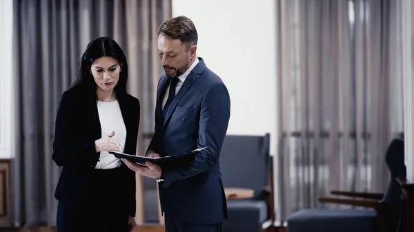 Business people looking at papers in lobby of restaurant — Stock Photo