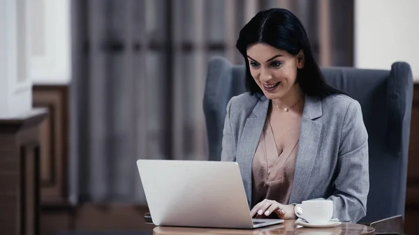Усміхнена жінка дивиться на ноутбук у фойє ресторану — стокове фото