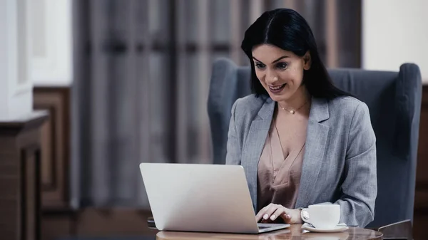 Lächelnde Frau blickt in Lobby des Restaurants auf Laptop — Stockfoto