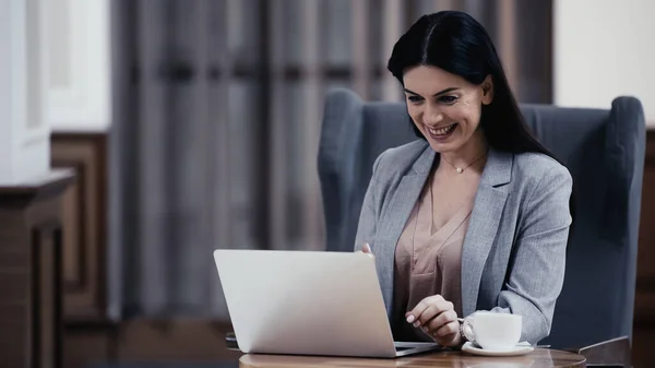 Freudige Frau blickt in Lobby des Restaurants auf Laptop — Stockfoto