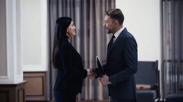 Side view of happy business people shaking hands in lobby of restaurant — Foto stock