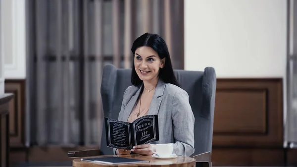 Happy businesswoman holding menu in lobby of restaurant — Photo de stock