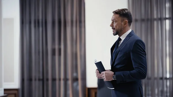 Bearded businessman holding paper folder and looking away — Photo de stock