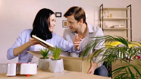 Couple parlant et emballant le cadre photo dans la boîte à la maison — Photo de stock