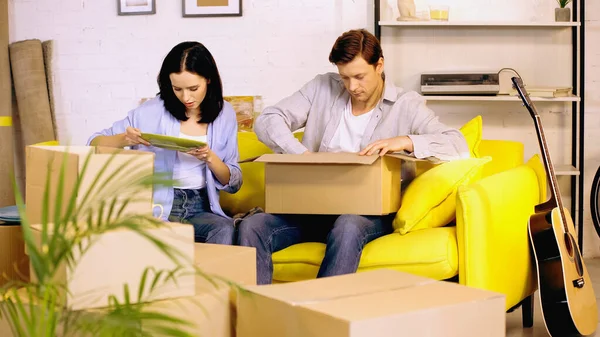 Pareja placa de desembalaje de cajas de cartón en el sofá - foto de stock