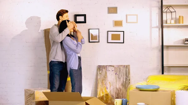 Man covering eyes of girlfriend in new house — Stock Photo