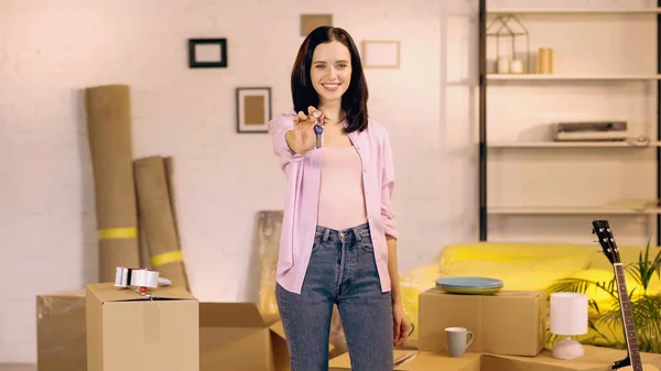 Счастливая молодая женщина показывает ключи на камеру в новом доме — стоковое фото