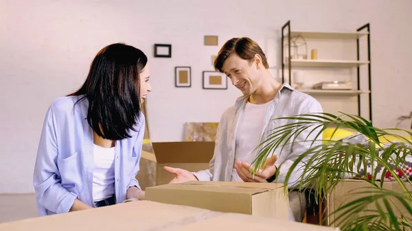 Happy couple looking at each other while packing box — Stock Photo