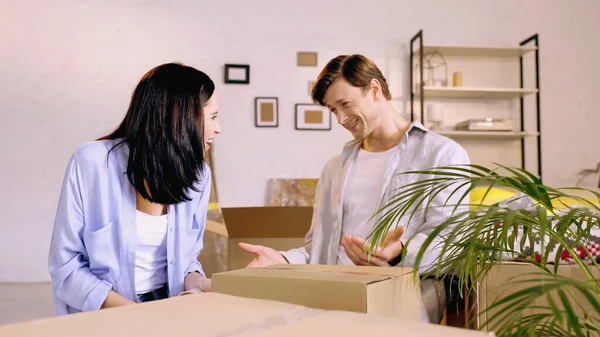 Feliz pareja mirando el uno al otro mientras que la caja de embalaje - foto de stock