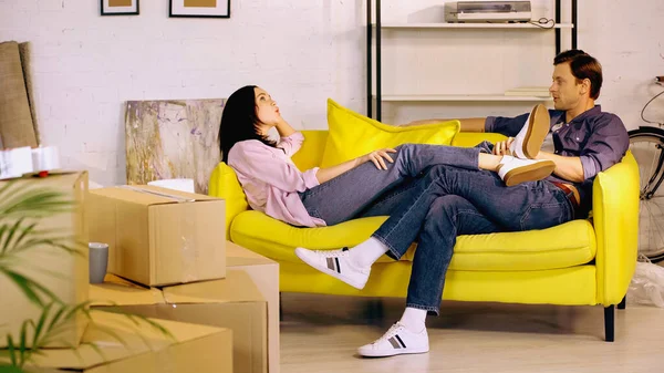 Mann und Frau ruhen sich auf Couch in der Nähe von Kartons aus — Stockfoto