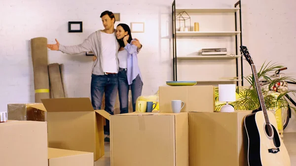 Blurred man hugging girlfriend and showing new home — Stock Photo