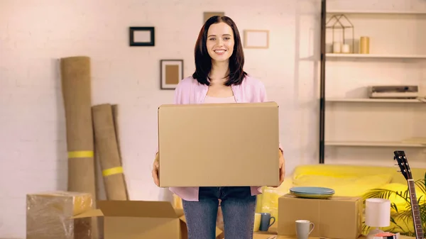 Happy woman holding carton box in new home — Stock Photo