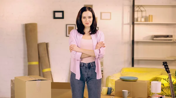 Pleased woman standing with crossed arms in new home — Stock Photo