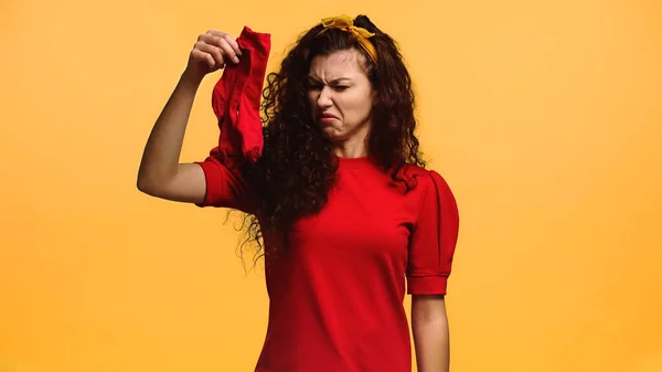 Mujer disgustada sosteniendo calcetines malolientes aislados en naranja - foto de stock