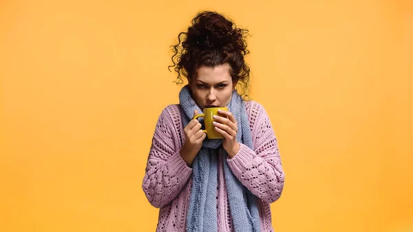 Femme en pull tricoté et écharpe tenant tasse de boisson chaude isolée sur orange — Photo de stock