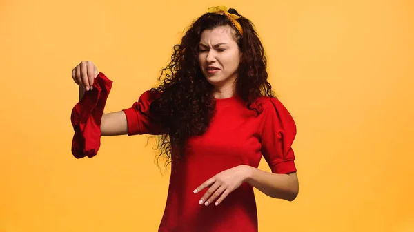 Displeased woman grimacing while holding stinky socks isolated on orange — Stock Photo