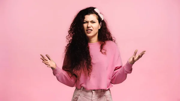 Angry woman showing indignation gesture while looking at camera isolated on pink — Stock Photo
