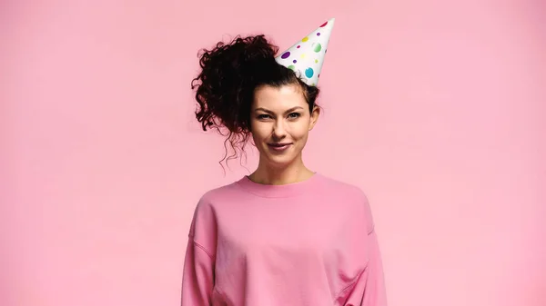 Donna bruna con i capelli ondulati che indossa il cappuccio del partito isolato sul rosa — Foto stock