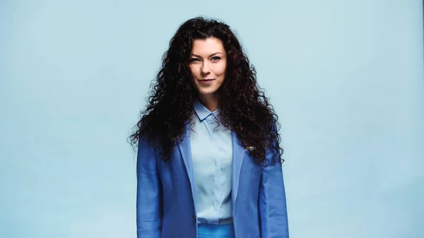 Femme positive en blazer bleu souriant à la caméra isolée sur bleu — Photo de stock