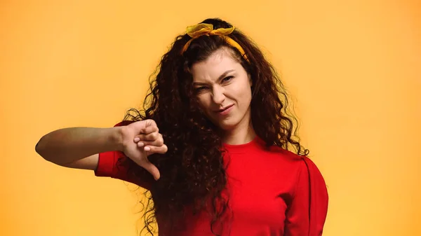 Donna scontenta con i capelli ricci mostrando pollice verso il basso isolato su arancione — Foto stock