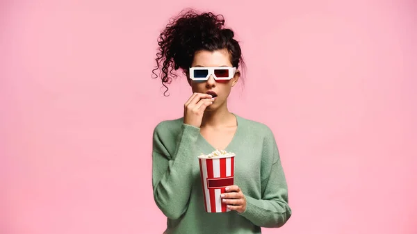 Überraschte Frau in 3D-Gläsern isst Popcorn isoliert auf rosa — Stockfoto