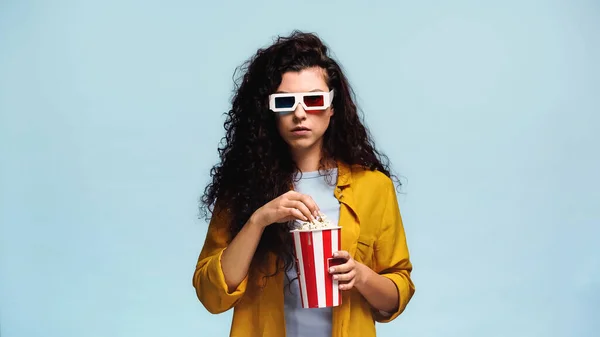 Jovem mulher em óculos 3d comer pipoca isolada em azul — Fotografia de Stock