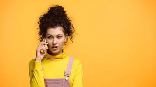 Femme concentrée parlant sur téléphone mobile isolé sur orange — Photo de stock