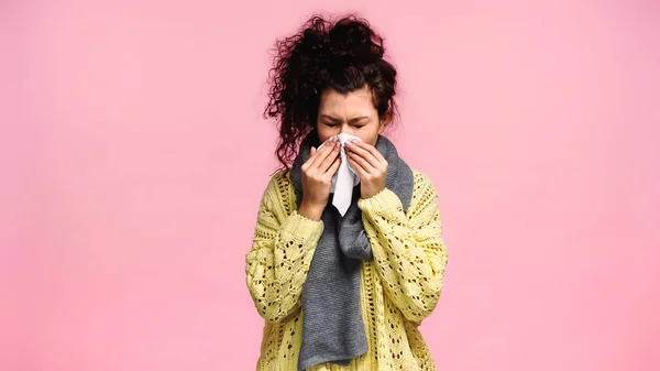 Sick woman with closed eyes sneezing in paper napkin isolated on pink — Stock Photo