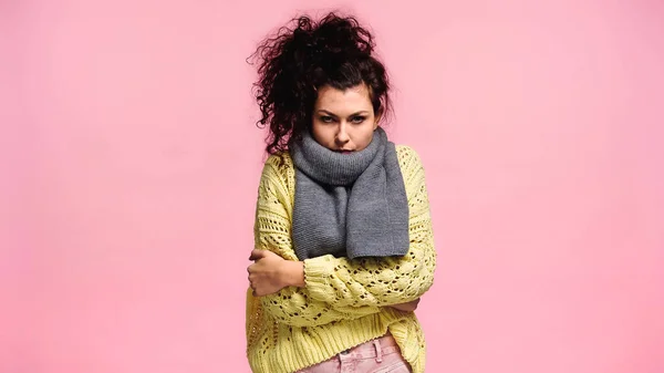 Displeased woman freezing in sweater and scarf while looking at camera isolated on pink — Stock Photo