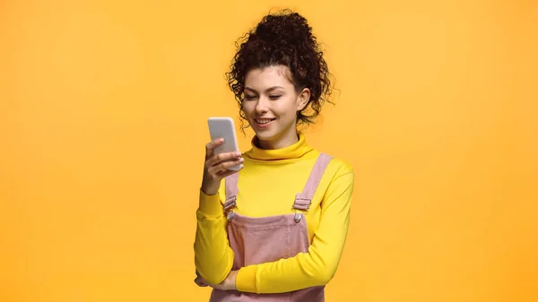 Sorrindo morena mulher mensagens no telefone celular isolado na laranja — Fotografia de Stock