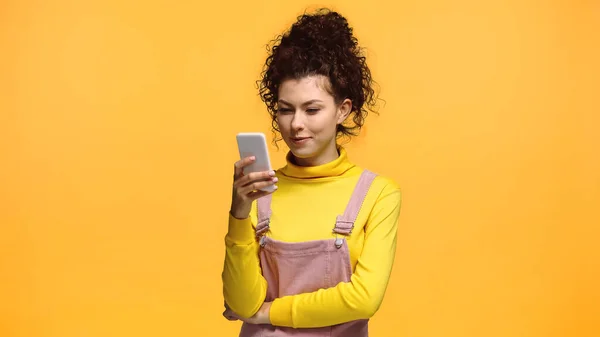 Donna positiva con capelli ricci chatta su smartphone isolato su arancione — Foto stock